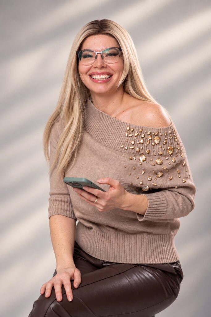Portret editorial cu Ioana Dosinescu zâmbind și ținând telefonul