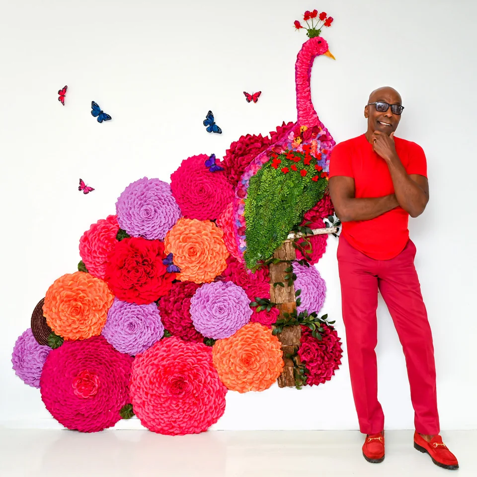 Preston Bailey alături de o sculptură florală monumentală în forma unui păun